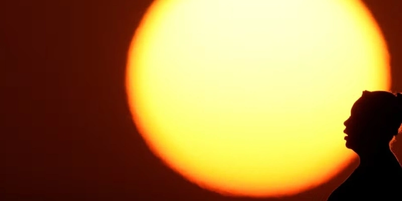 Silhueta de uma mulher contra o sol poente - AP Photo/Charlie Riedel