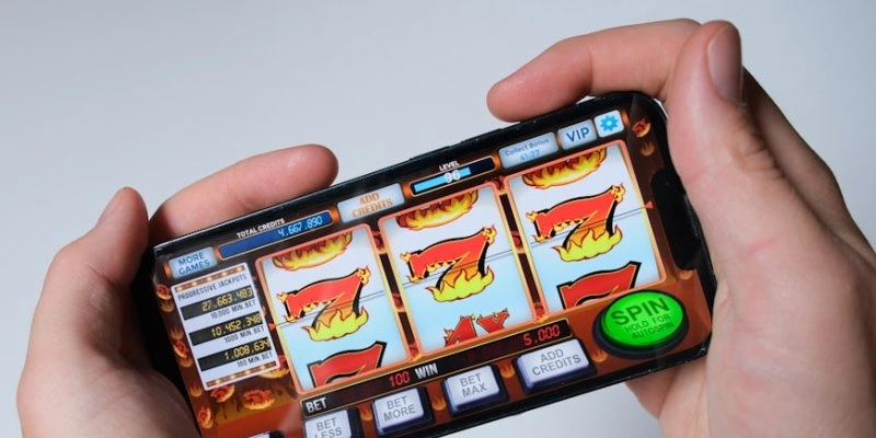 Duas mãos seguram um celular na horizontal, com um jogo de cassino online em execução na tela - Niek Doup/Unsplash